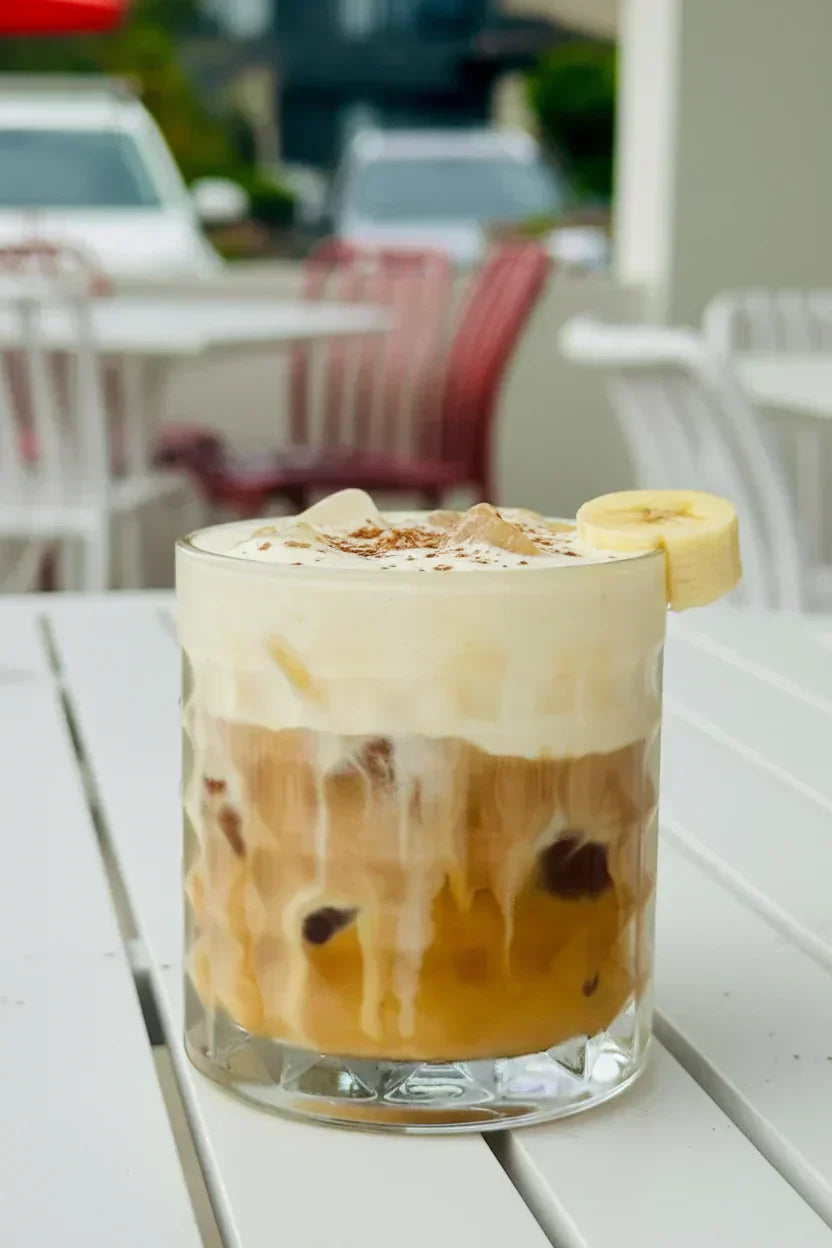 Banana Bread Iced Latte with banana bread cold foam, fresh banana slice and cinnamon sugar garnish