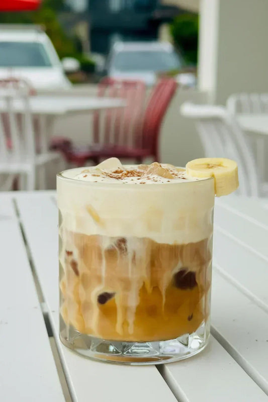 Banana Bread Iced Latte with banana bread cold foam, fresh banana slice and cinnamon sugar garnish